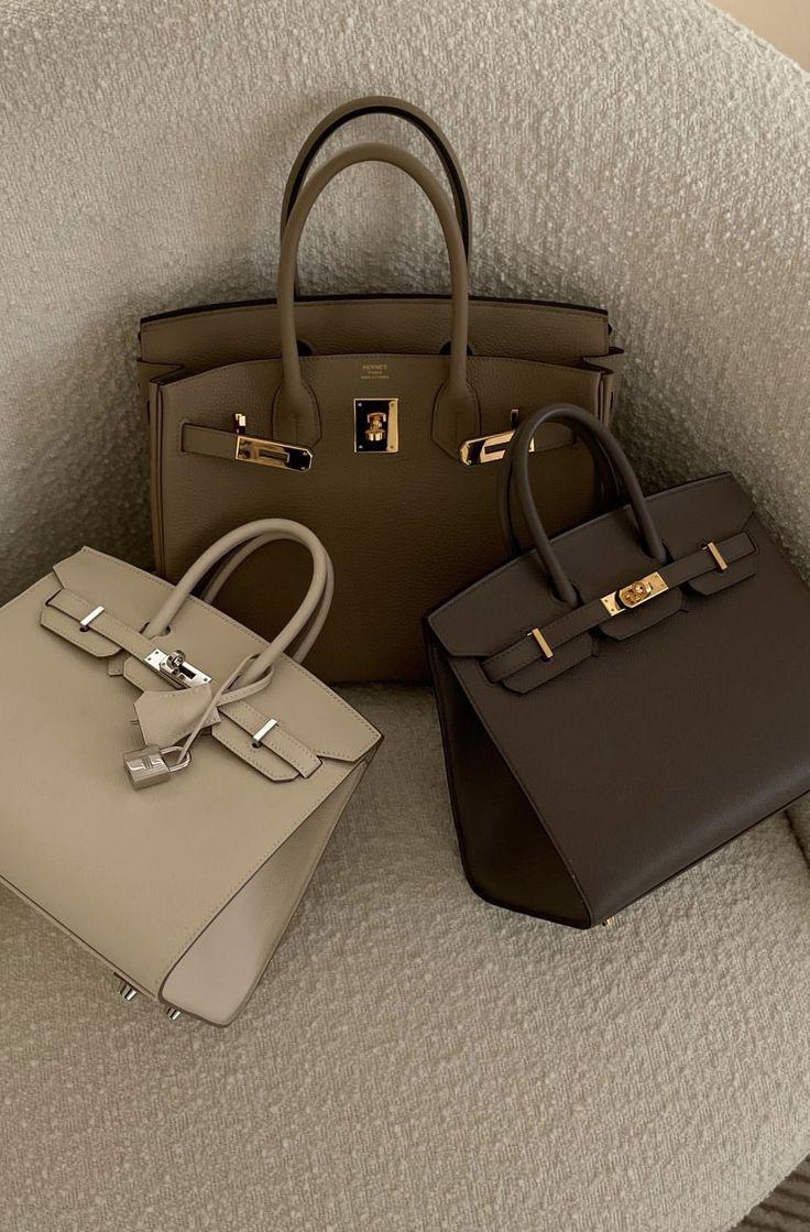 Three handbags in beige, brown, and black on a textured surface.